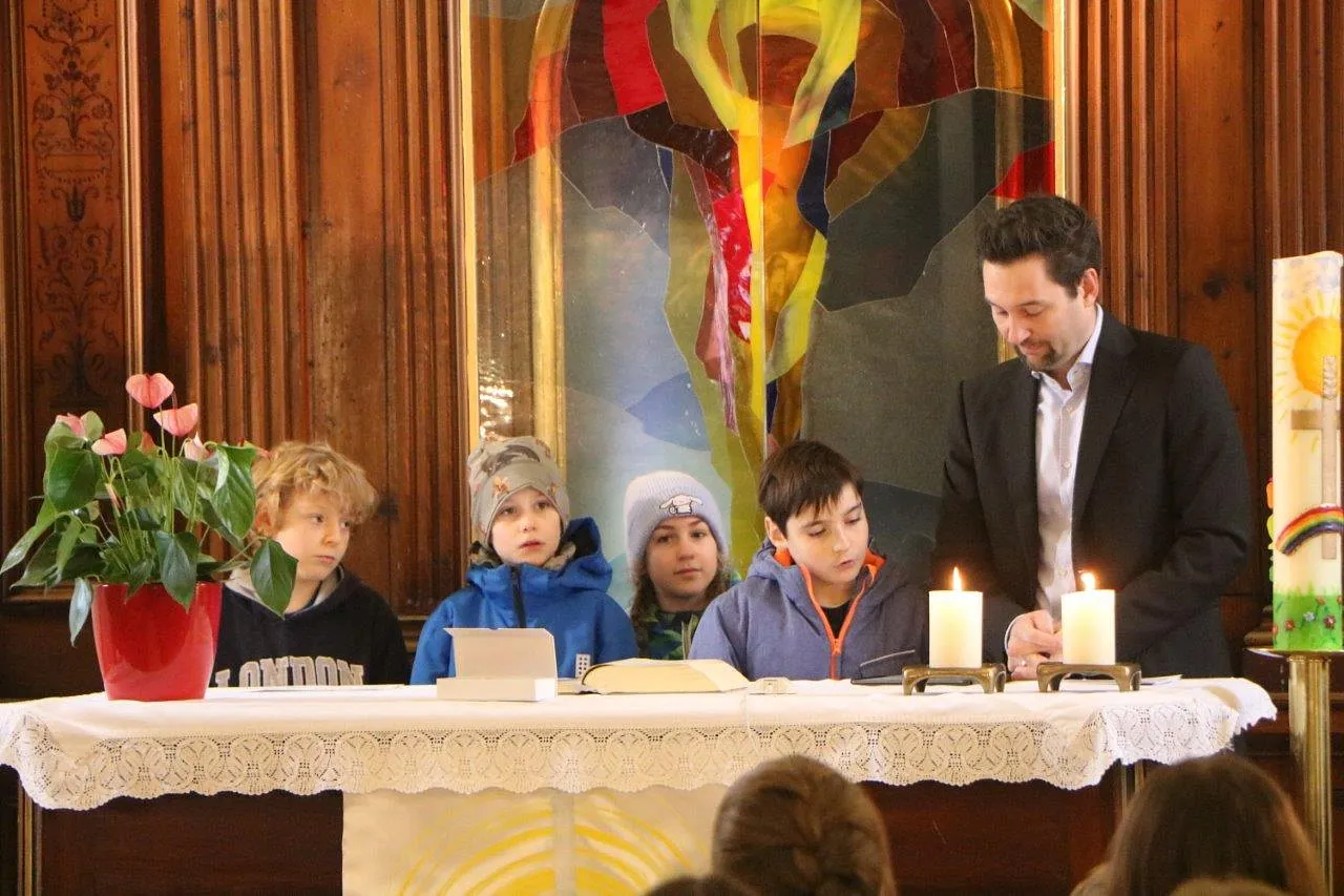 Kinder und ein Mann stehen hintewr dem Altar der Kirche