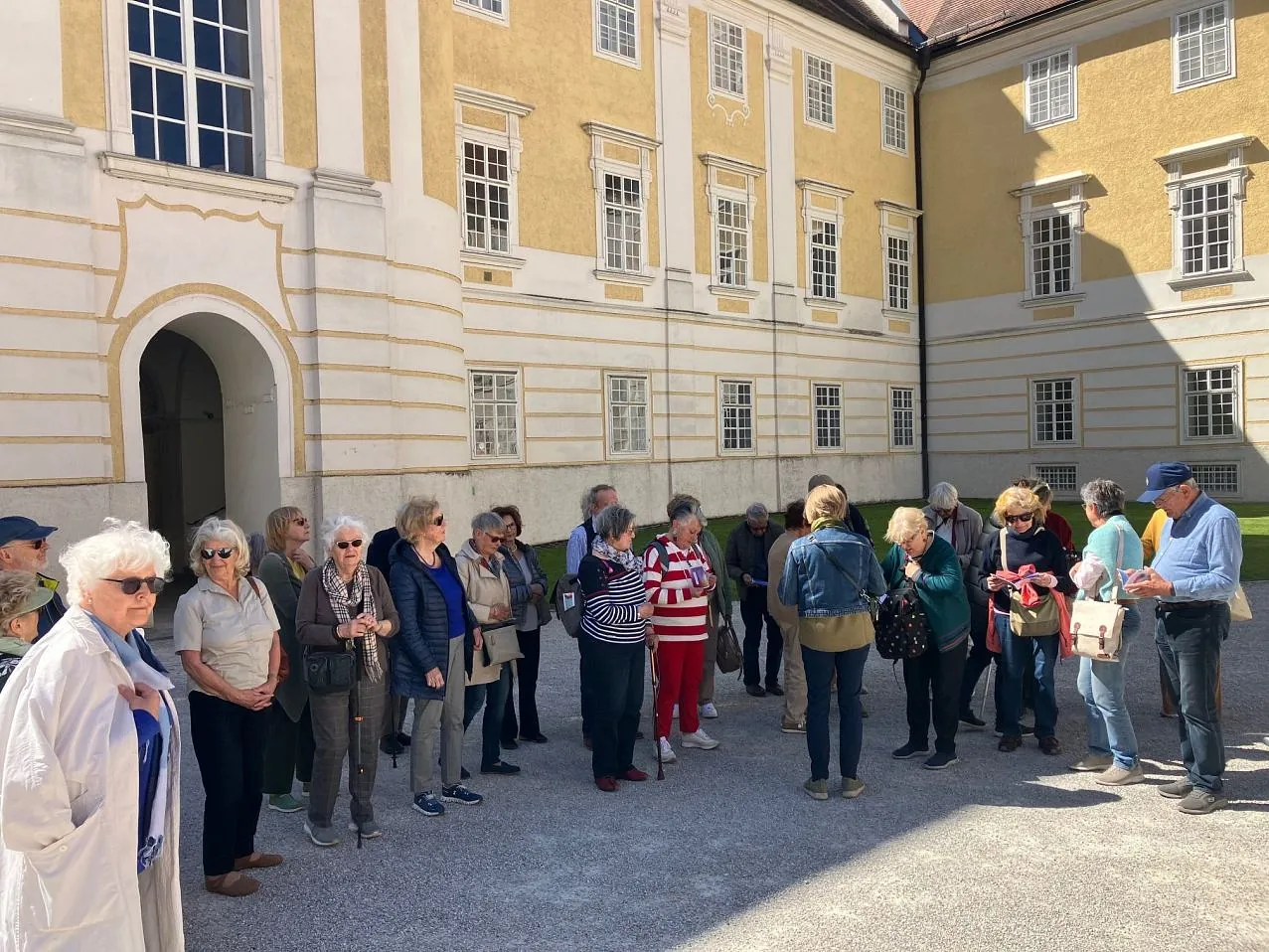Eine Gruppe von Senior:innen steht im Hof eines Stiftsgebäudes.
