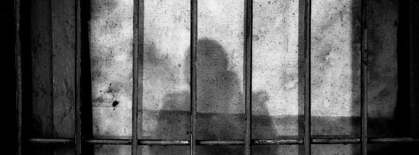 Schatteneiner Person hinter Gitterstäben