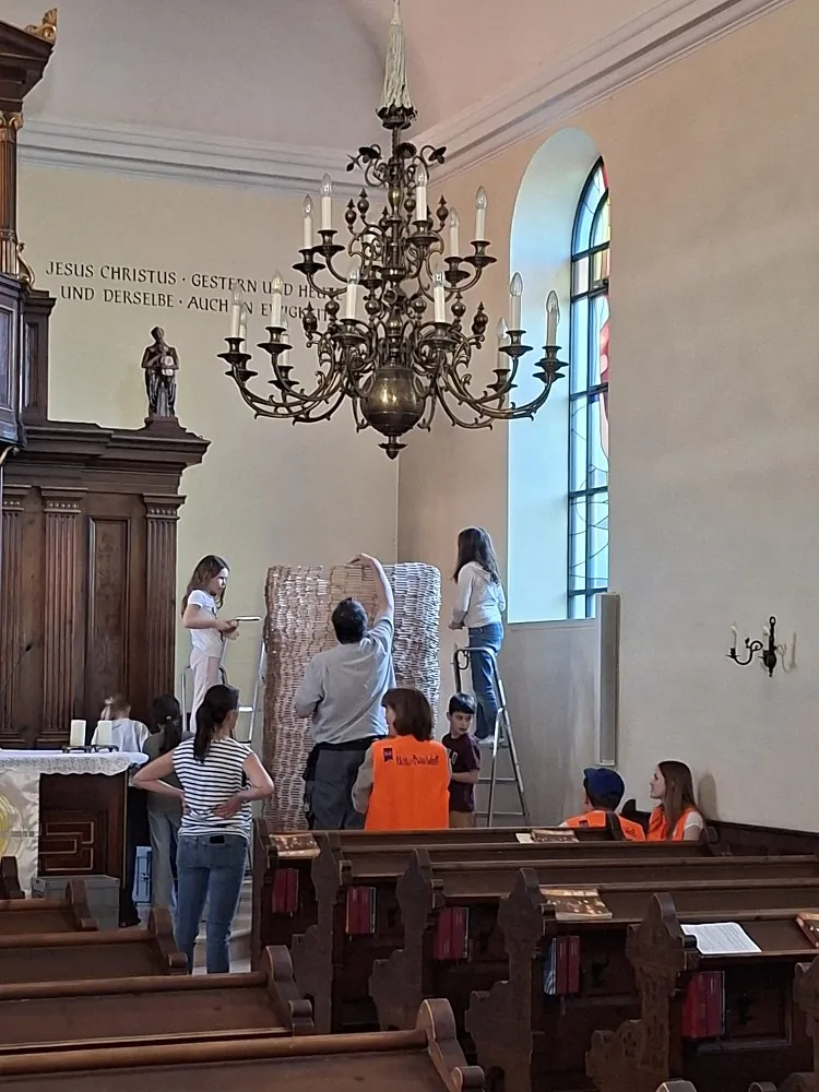In einer Kirche wird aus Holzbausteinen ein hoher Turm gebaut.